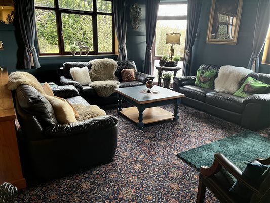 The lounge showing three leather sofas and view to the gardens